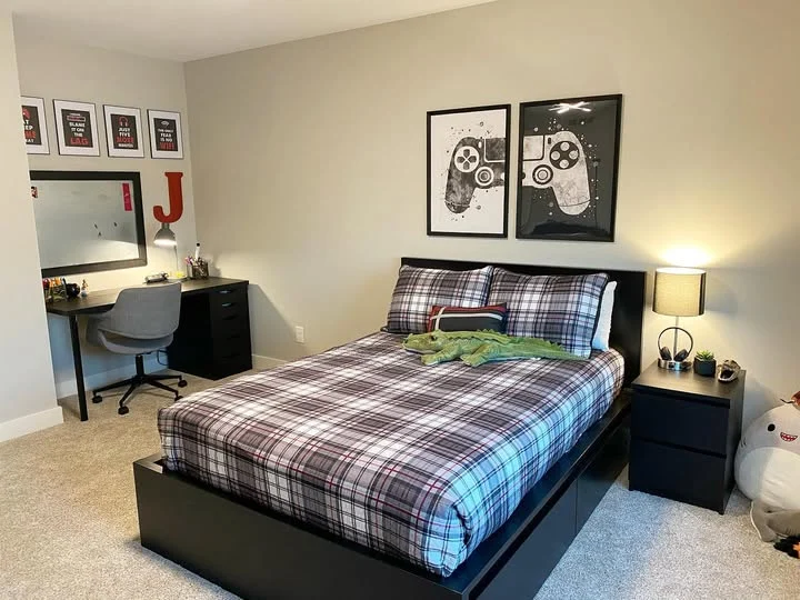 Boy’s bedroom with plaid bedding, black furniture, and sports wall art