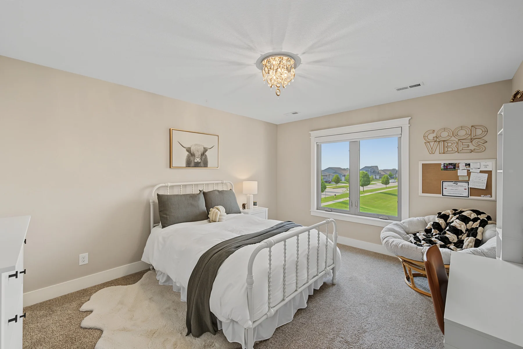 Teen bedroom with layered bedding, a patterned accent chair, and a desk beside the window